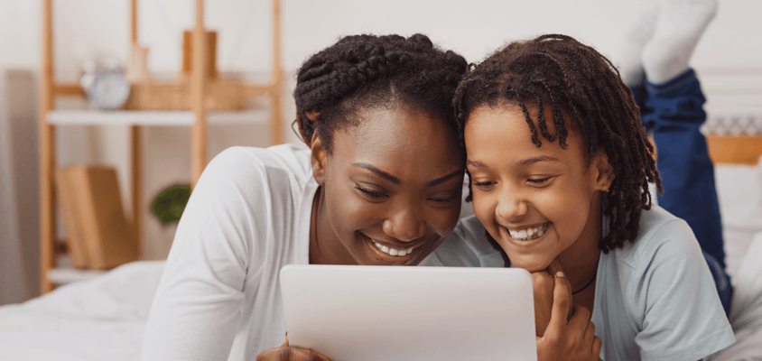 A parent and child look at a computer together and smile.  A parent and child look at a computer together and smile.
